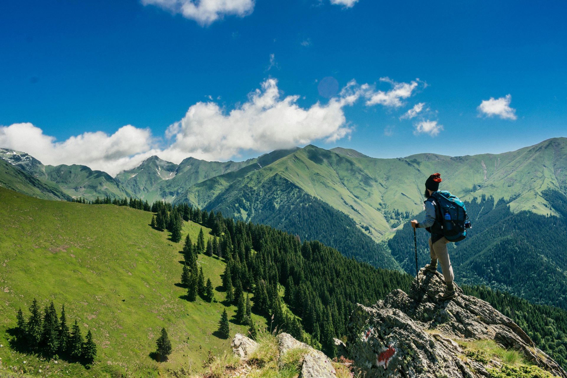 Randonneuse aventureuse profitant de vues à couper le souffle sur les montagnes verdoyantes de Roumanie sous un ciel bleu azur.