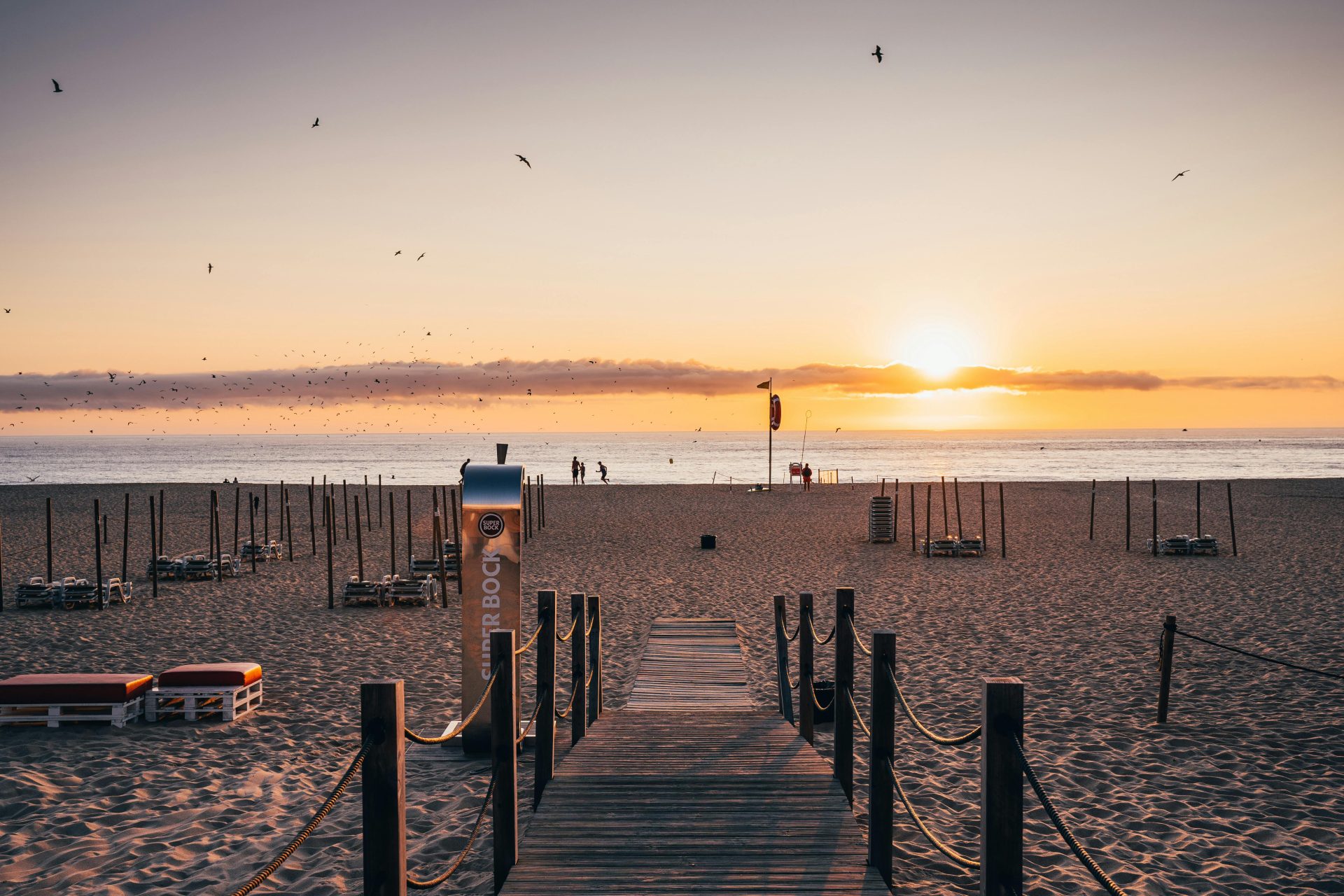 Vue paisible du coucher de soleil depuis une promenade en bord de mer menant à l'horizon calme de l'océan.